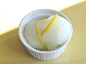 An overhead view of two scoops of lemon ice, garnished with lemon zest.