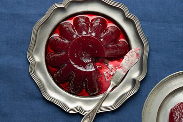 Silver platter of jellied cranberry sauce with a small plate of cranberry sauce in the bottom corner 
