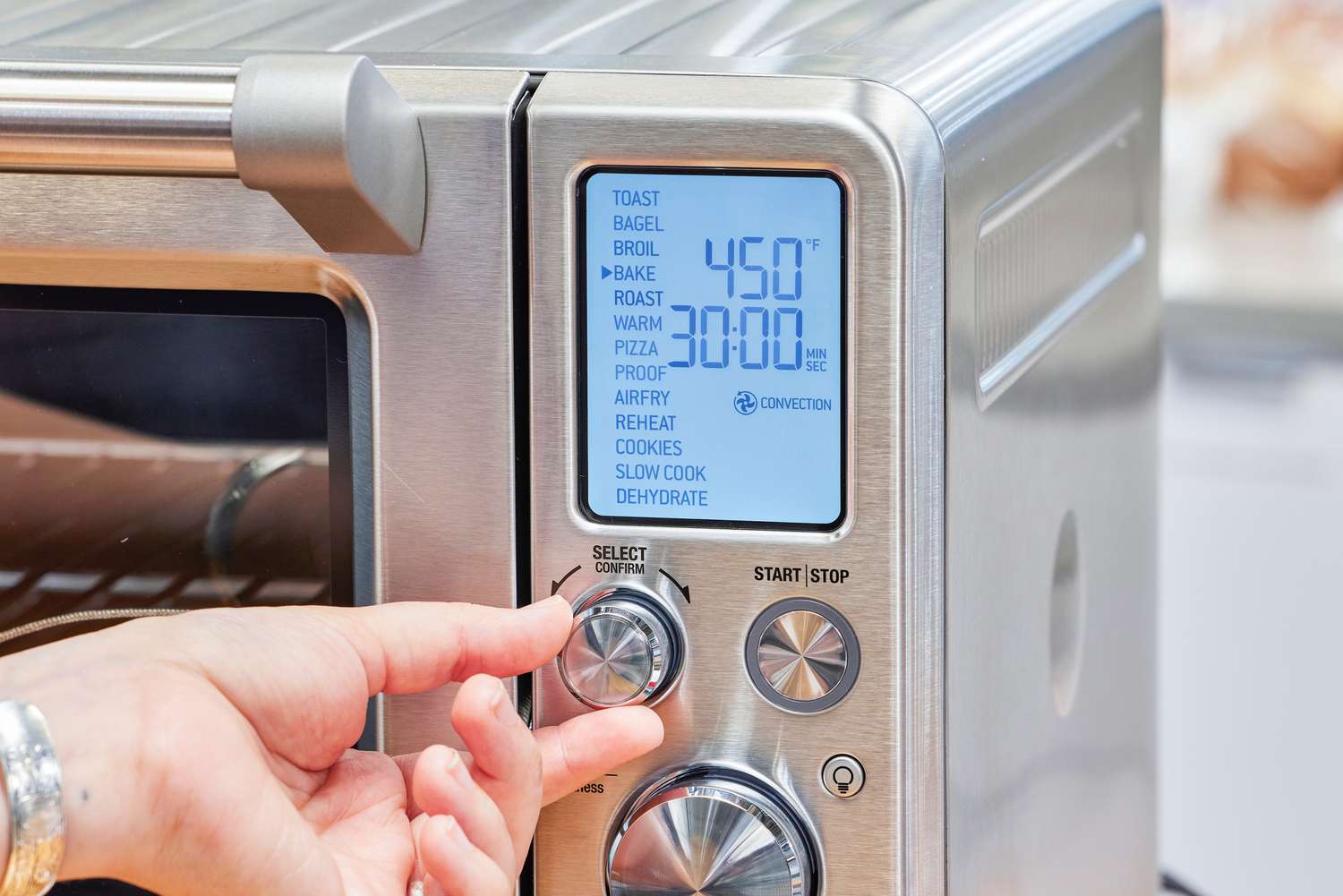 A hand turning a nob on the Breville the Smart Oven Air Fryer