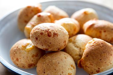 A bowl filled with golden brown cunapes, a South American cheesy bread