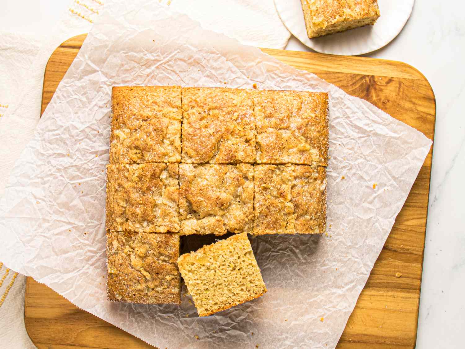 Squares of applesauce snack cake on a wooden board one piece slightly pulled out