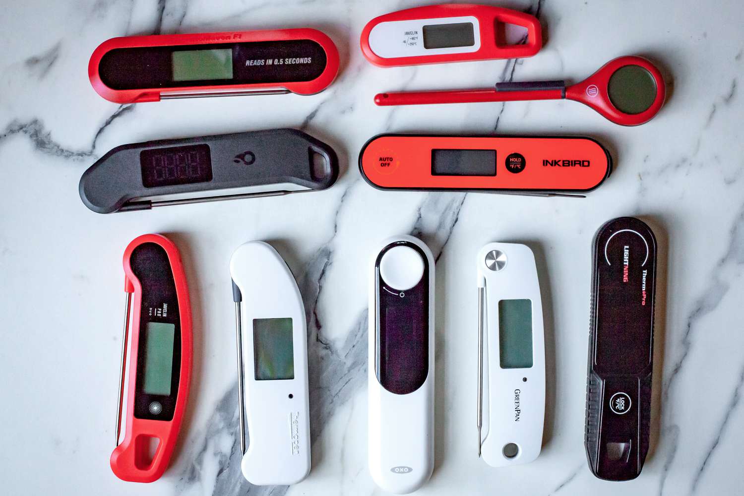 A number of instant-read thermometers on a marble countertop.