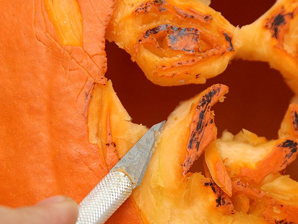 Cutting out large pieces from the design of a face in a pumpkin, using an X-ACTO knife
