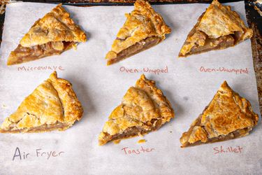 Slices of pie reheated using different methods including microwave oven wrapped oven unwrapped air fryer toaster and skillet