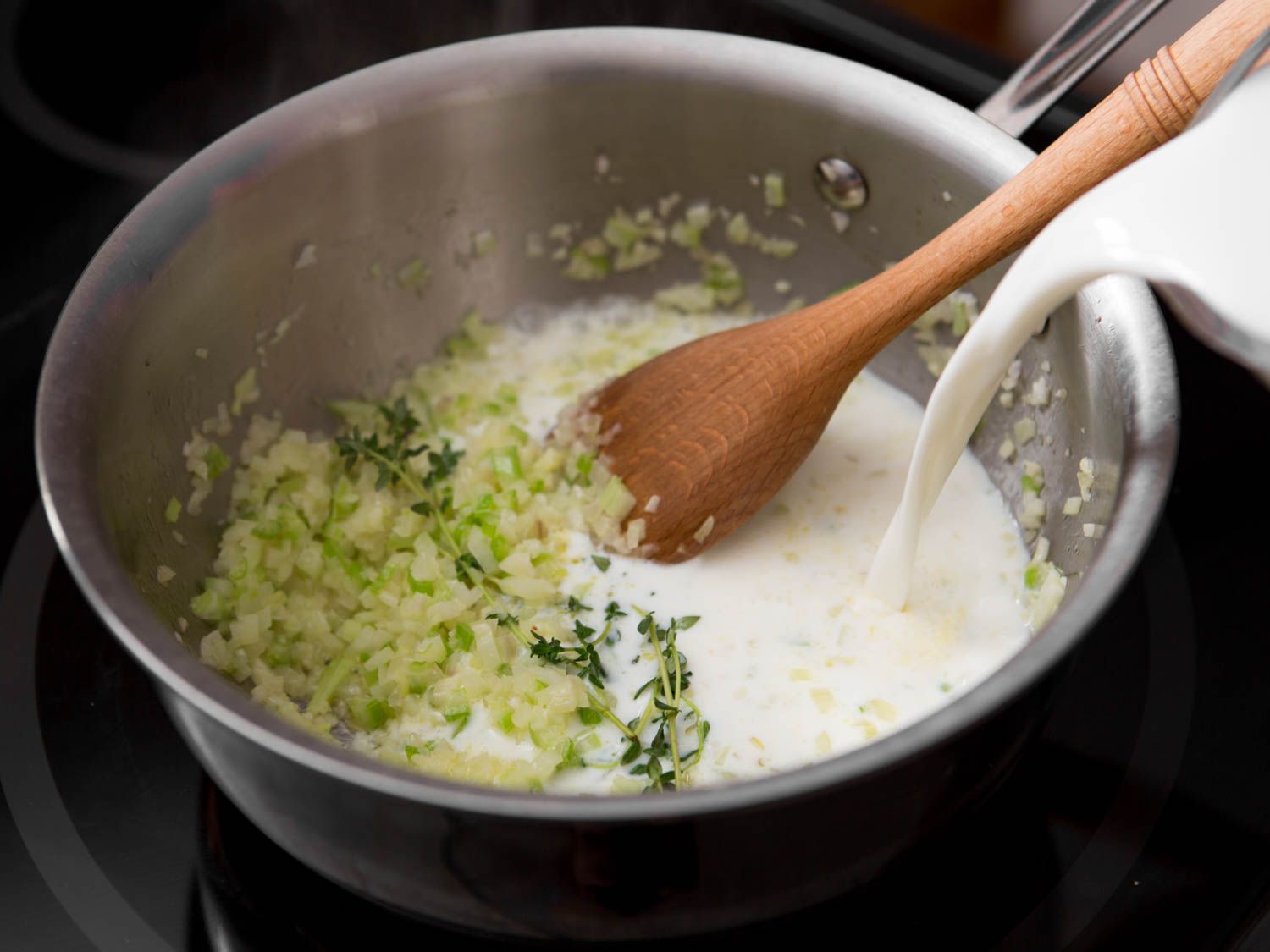 Milk is added to the pan along with the softened aromatics and herbs.