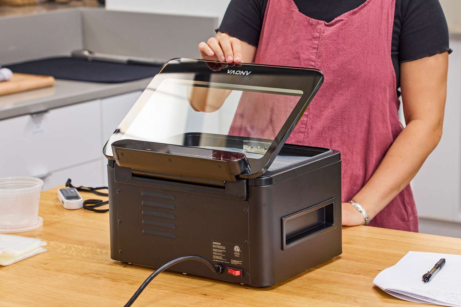 A person closes the top of the Anova Precision Chamber Vacuum Sealer