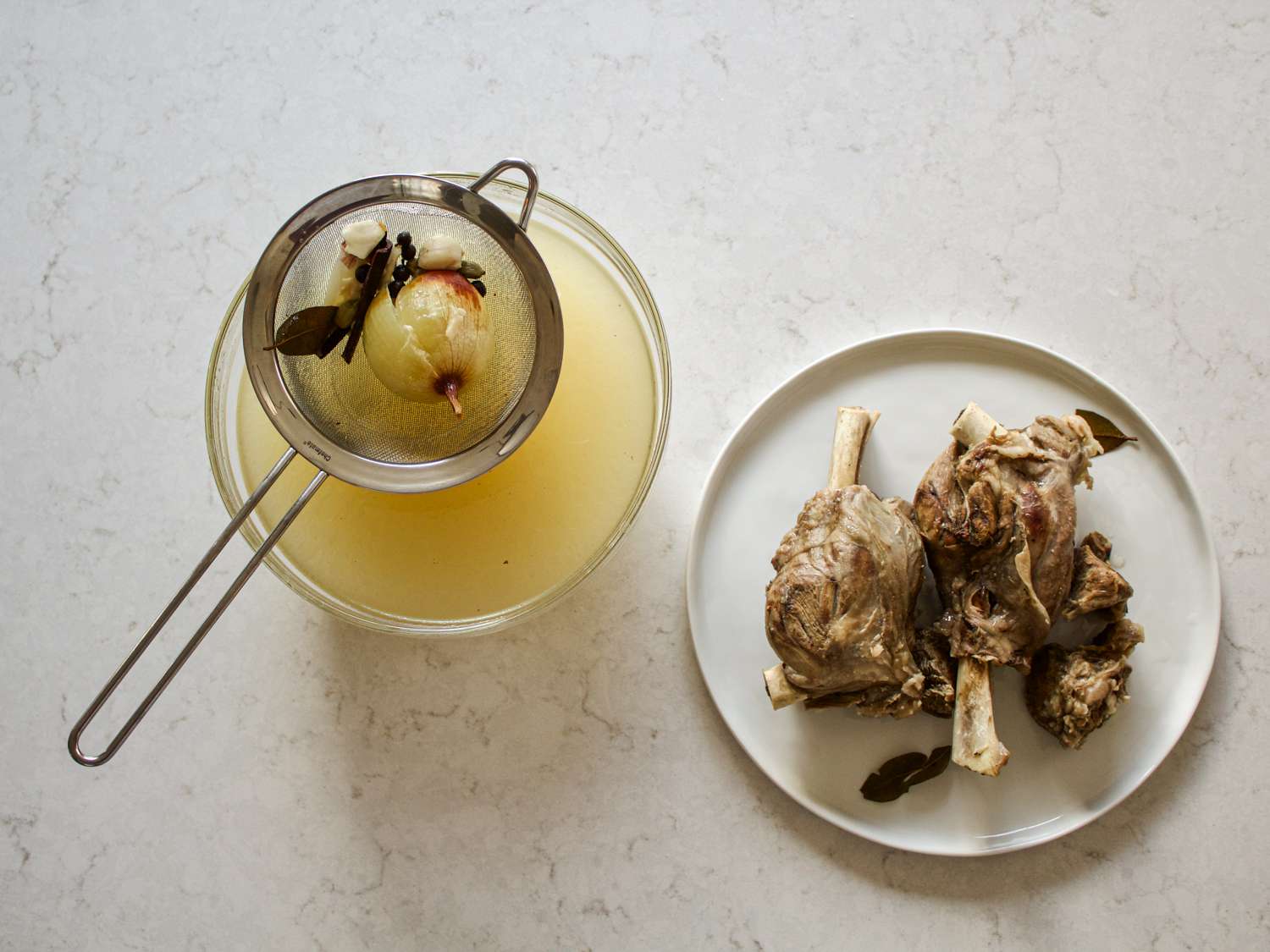 Lamb shanks on a platter next to strained broth