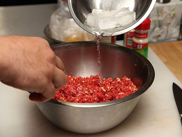 Ice and melted water is added to the bowl of ground meat.