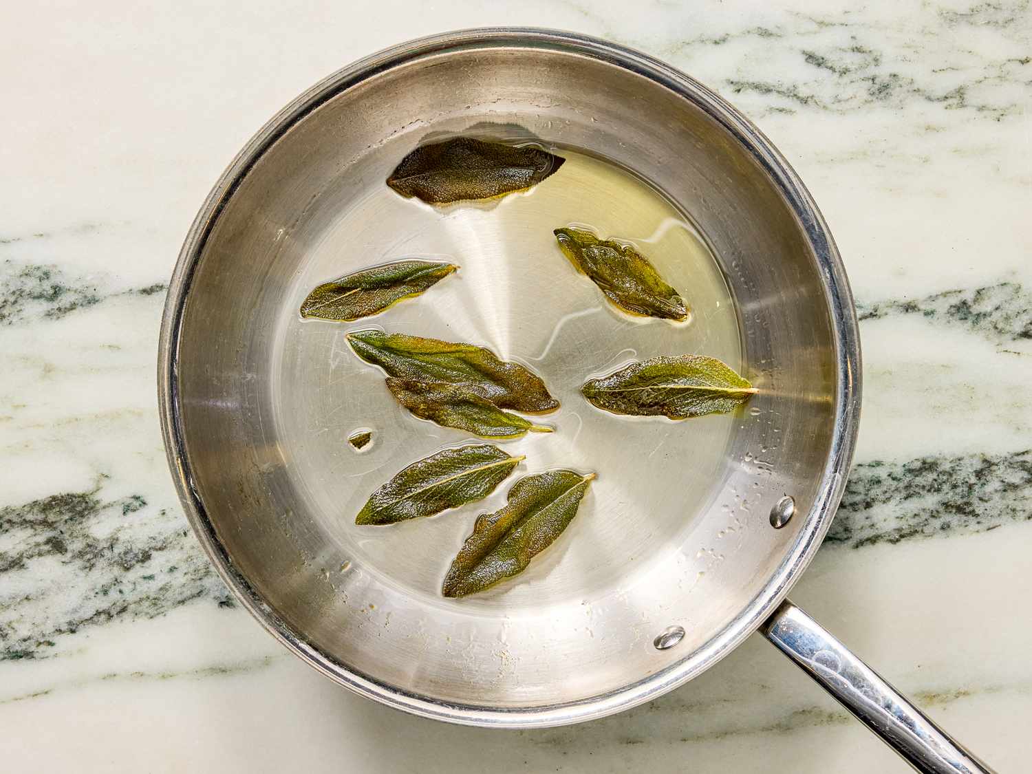 Sage leaves frying in a pan with oil