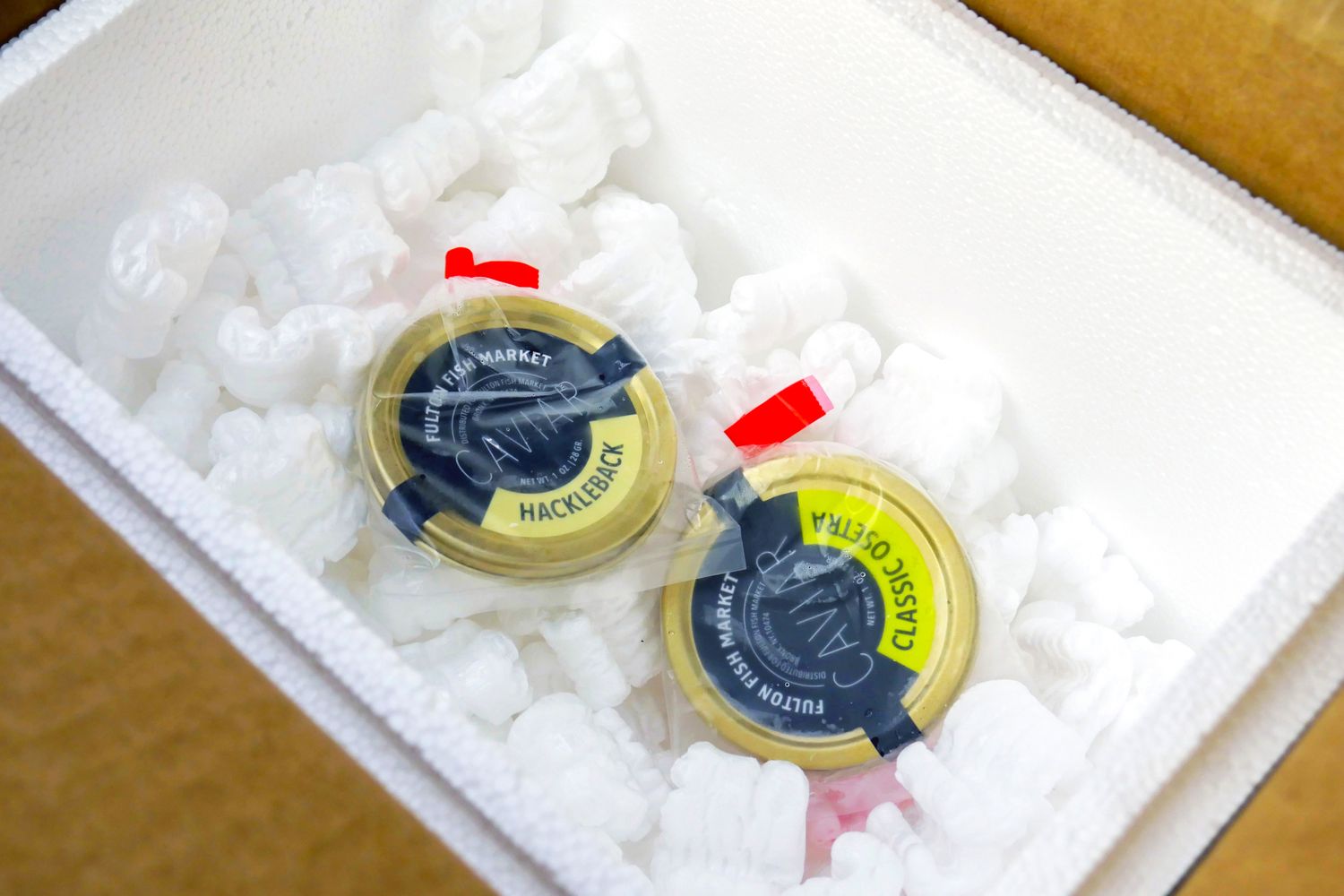 Two containers of Fulton Fish Market caviar in a box with packing material