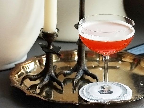 The paper plane cocktail on metal serving tray with candlesticks.