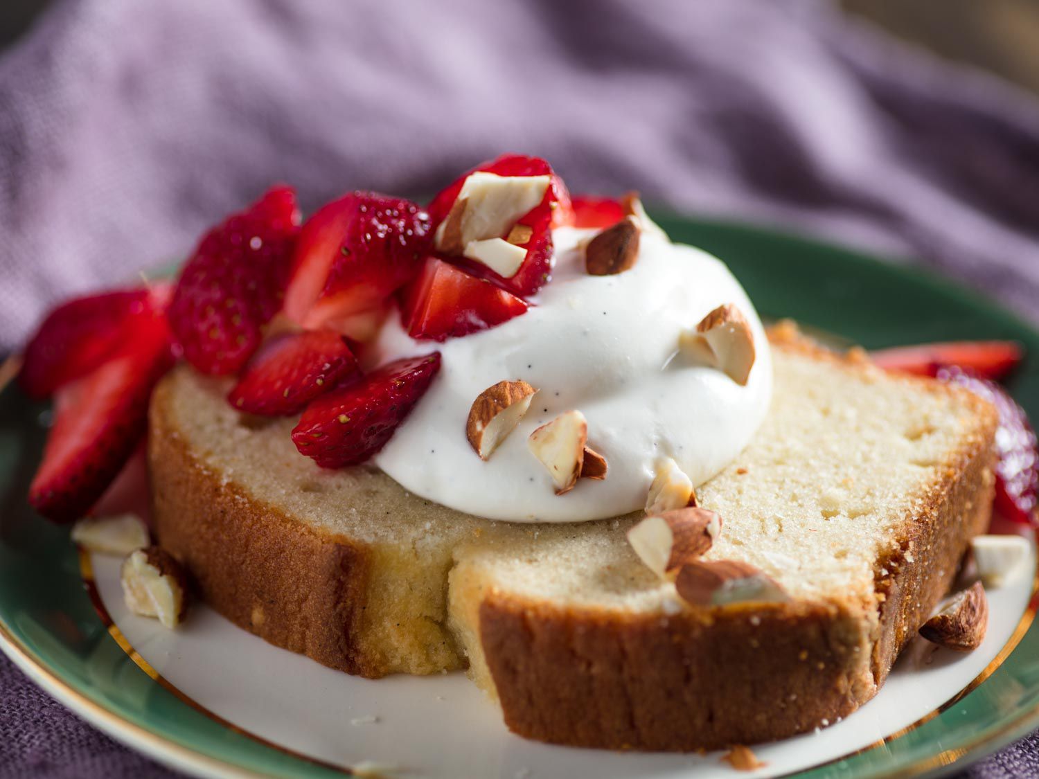 Whipped Greek yogurt, almonds, and strawberries on top of a slice of pound cake.