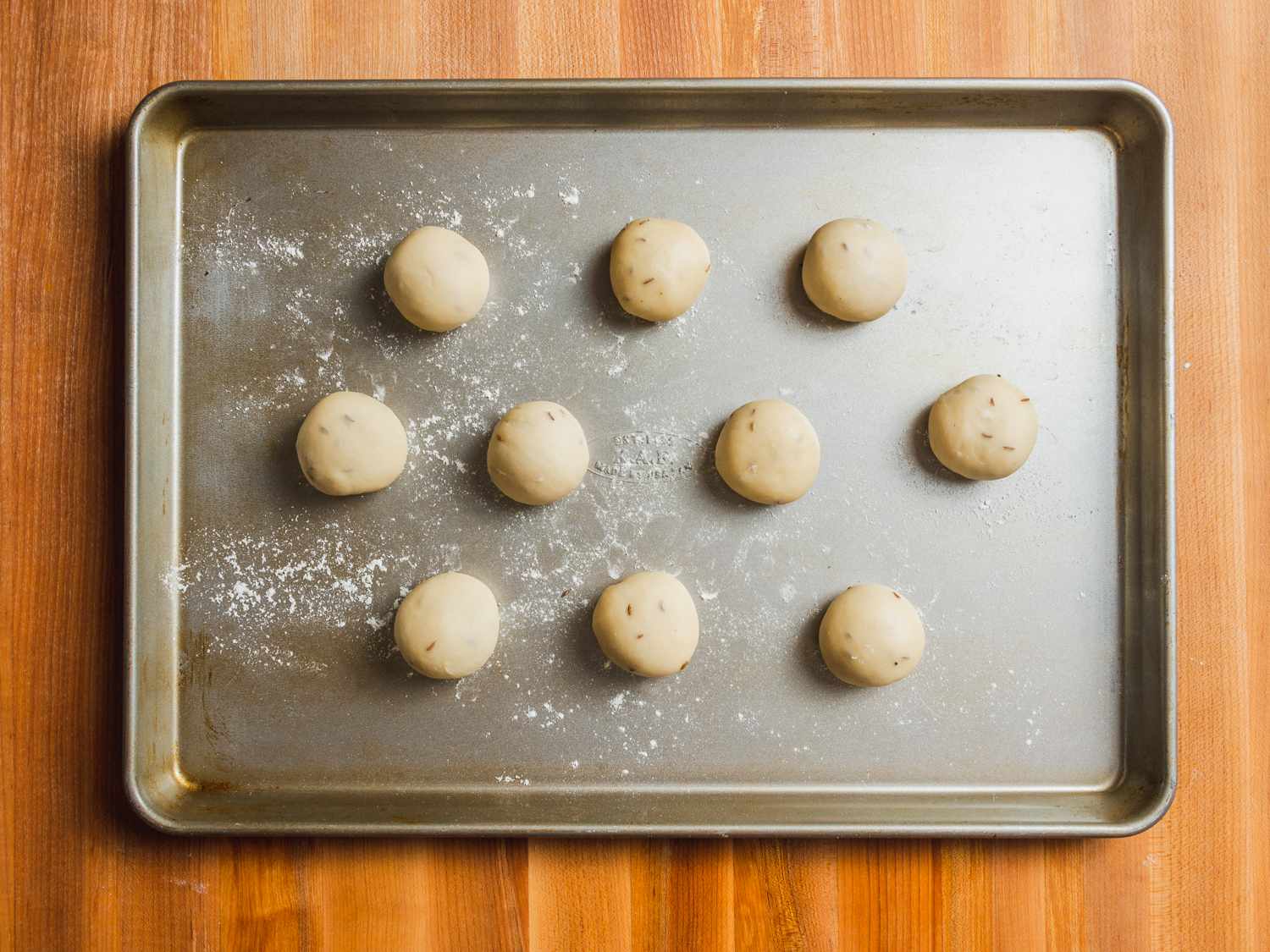 10 samosa pastry dough balls on a floured baking sheet.