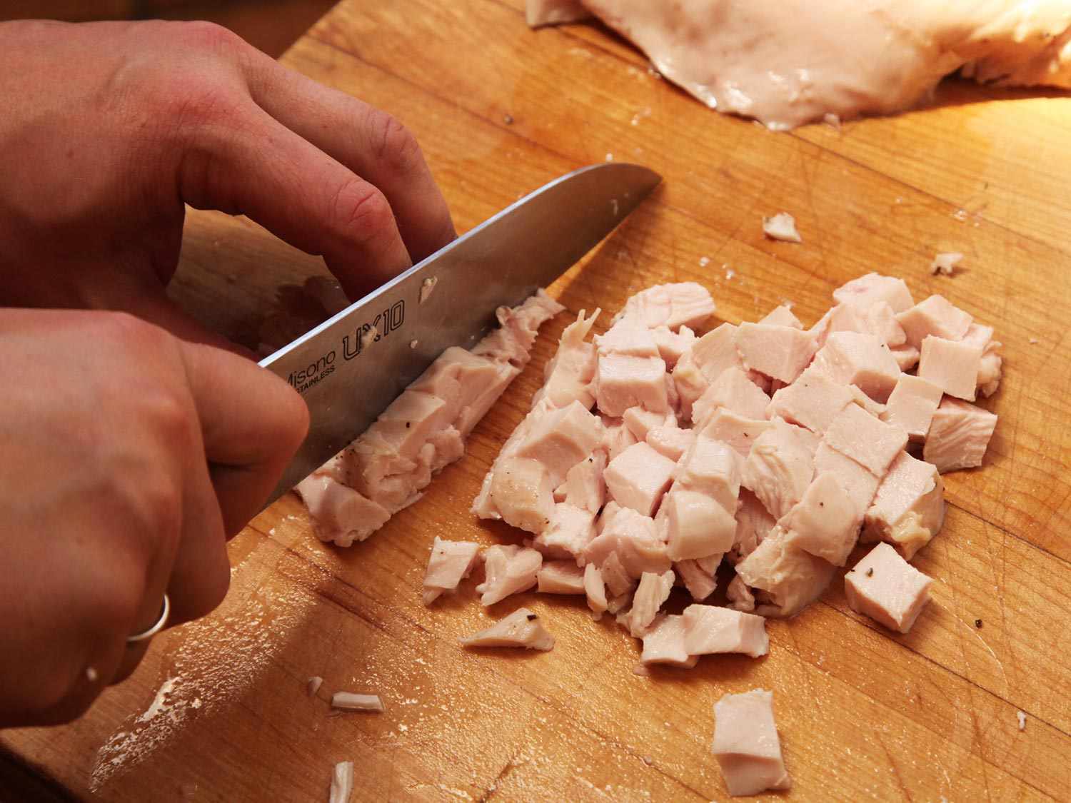 Dicing sous vide chicken breast on a cutting board for chicken salad.