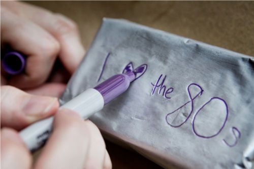 Closeup of the author writing "I [heart shape] the 80s" on the wax-paper wrapping of an ice cream sandwich.