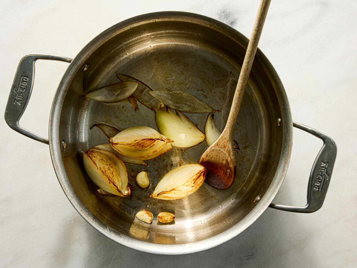 A saucepan with caramelized onions and garlic wooden spoon resting on the side
