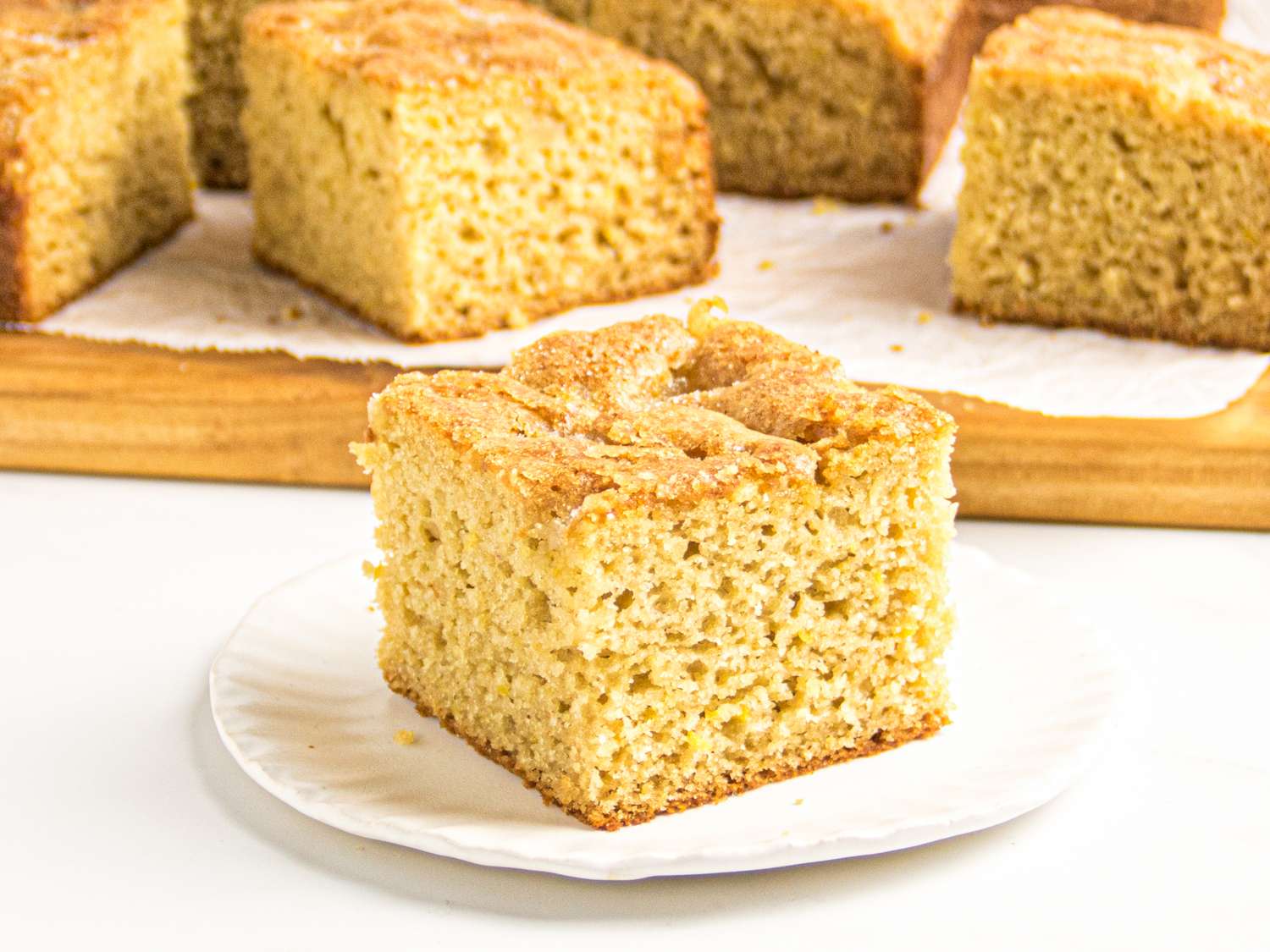 Slice of applesauce snack cake on a white plate with more cake pieces in the background
