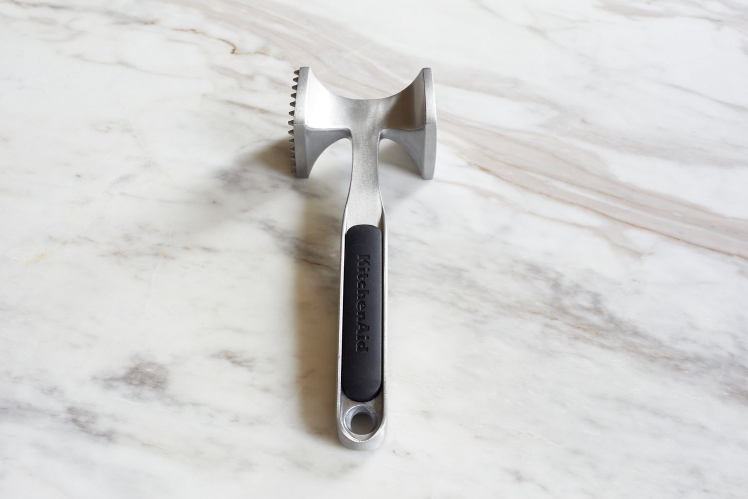 A mallet-style meat pounder on a marble surface