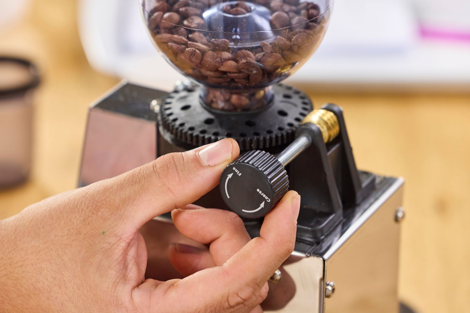 A hand adjusts the grind settings on the Lelit Fred Tempo Burr Grinder