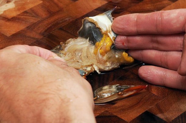 A hand pulling back the gills of a soft-shell crab