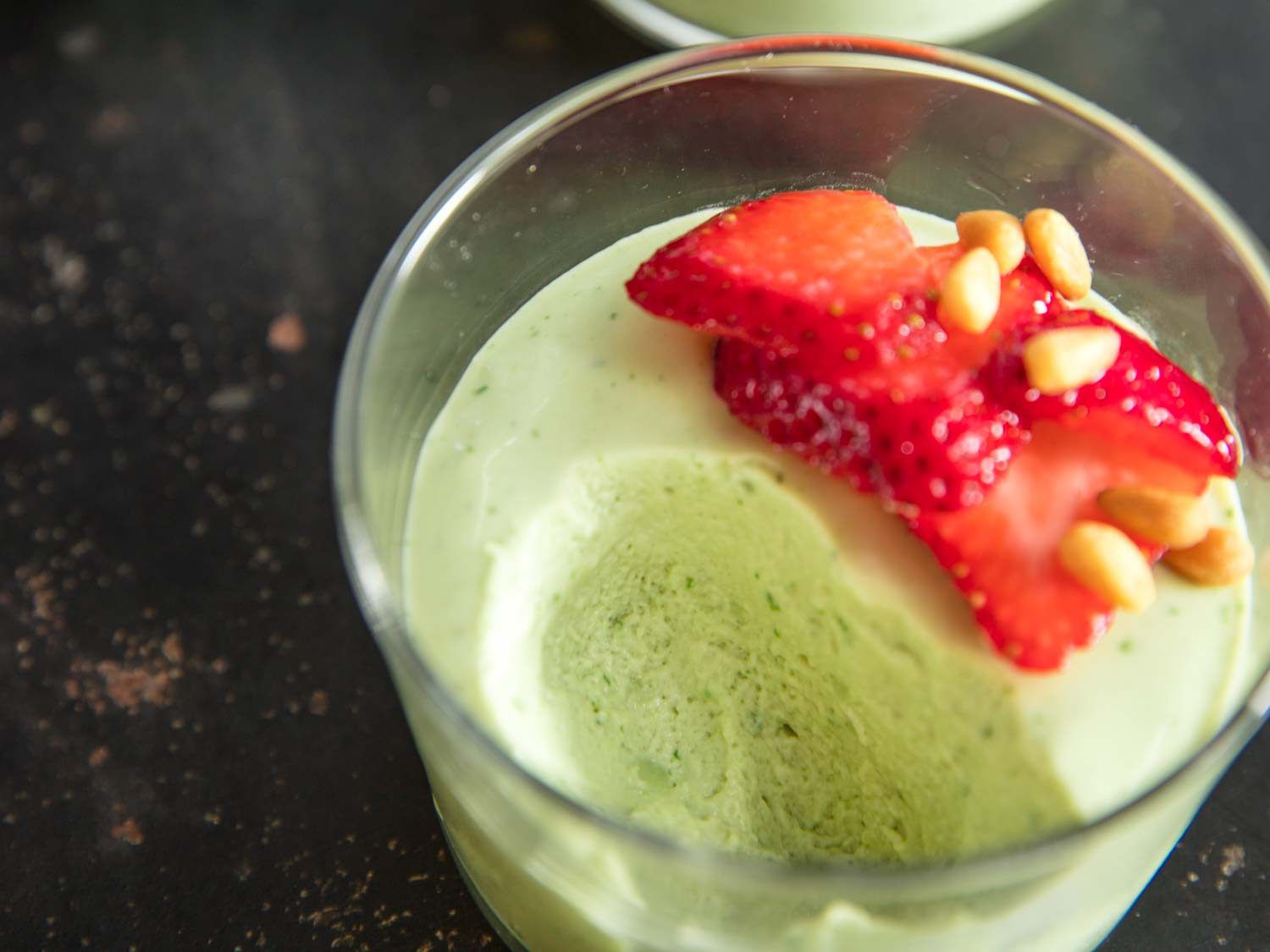 Closeup of a half-devoured glass of fresh basil mousse.