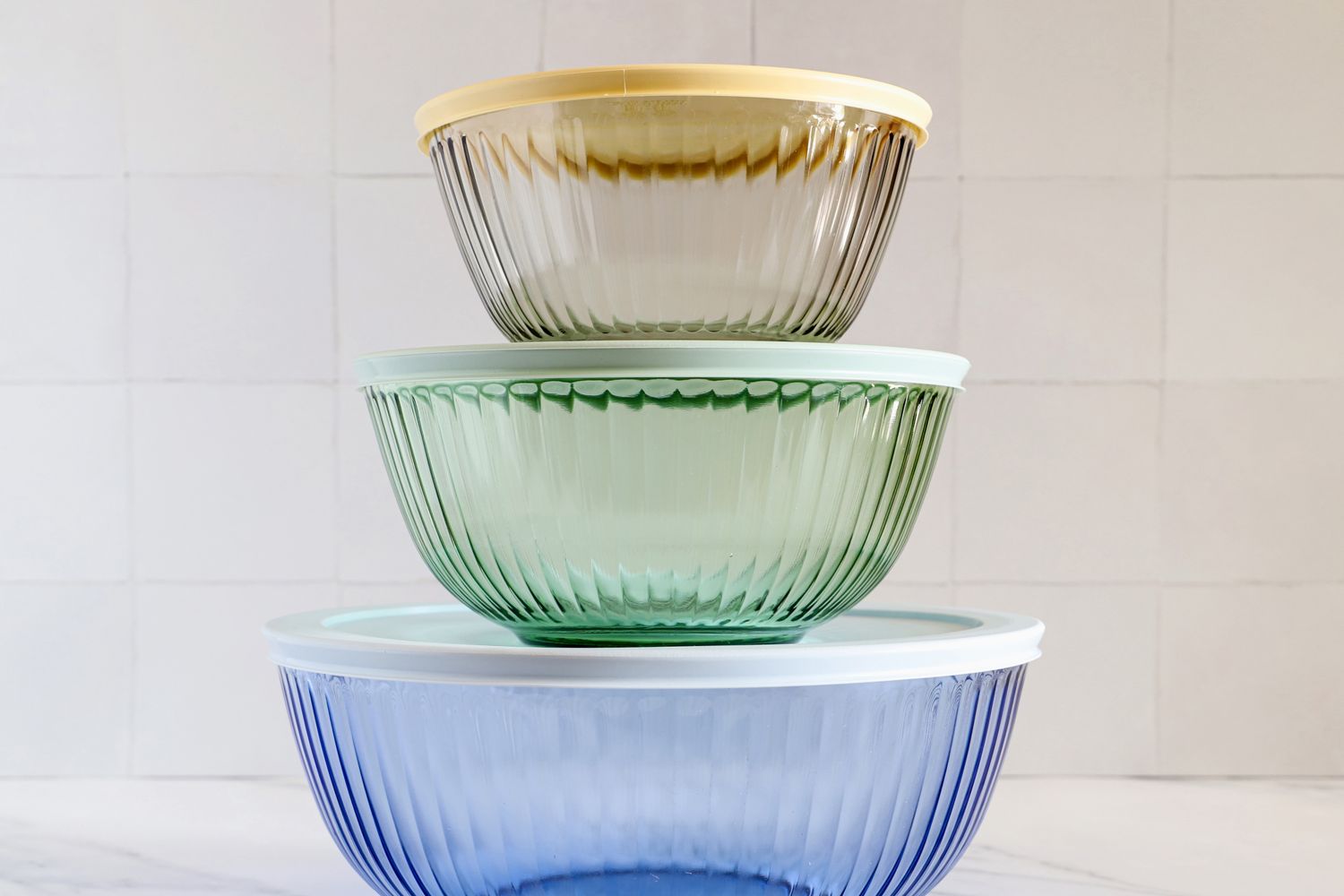 Pyrex Sculpted Tinted Glass Mixing Bowls set with their lids on, stacked on a countertop