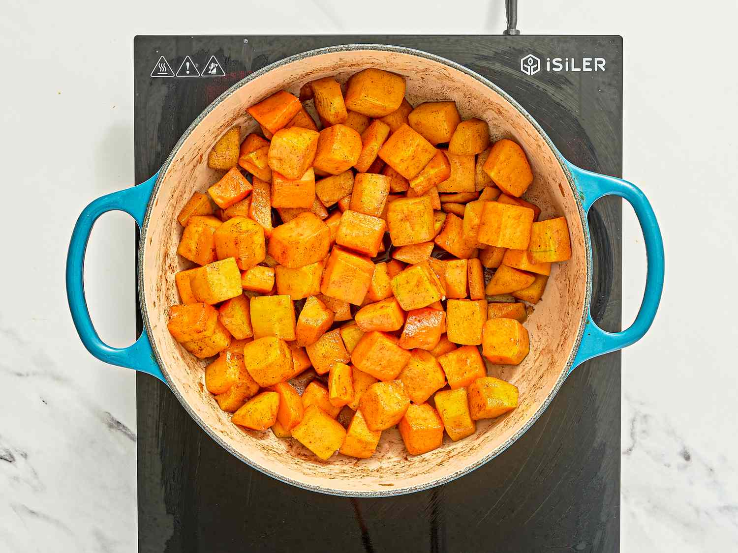 Diced sweet potatoes cooking in a pot on an induction stove