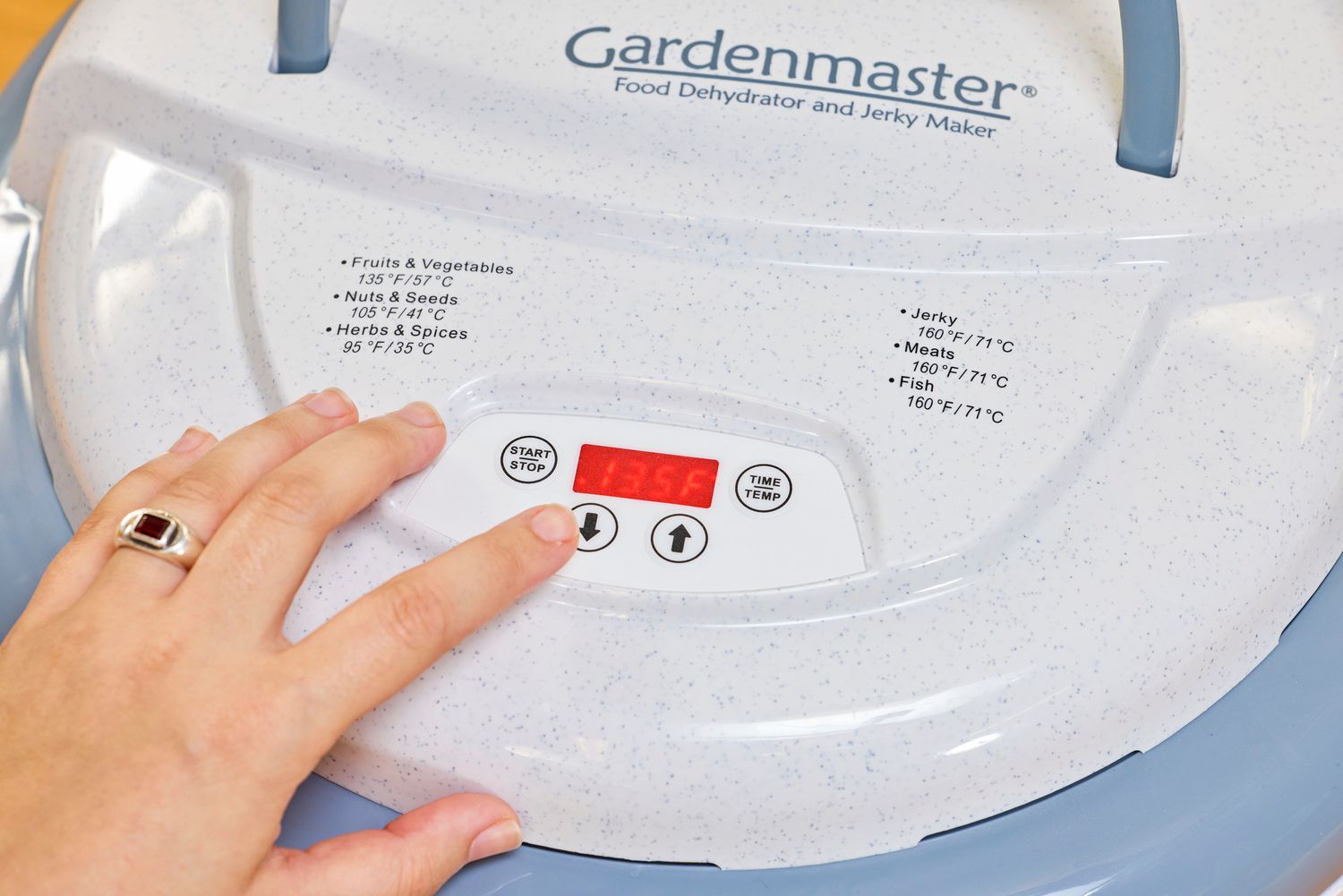 A person pressing a button of Nesco Gardenmaster Digital Pro Food Dehydrator