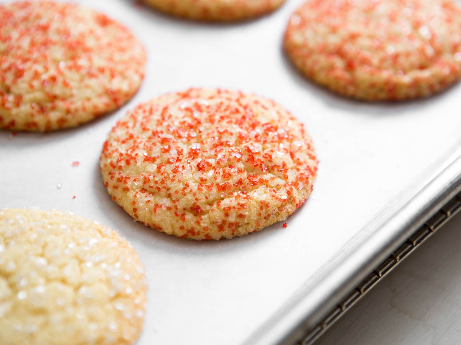 Closeup of a tray of soft, pillowy sugar cookies decorated with red sugar.