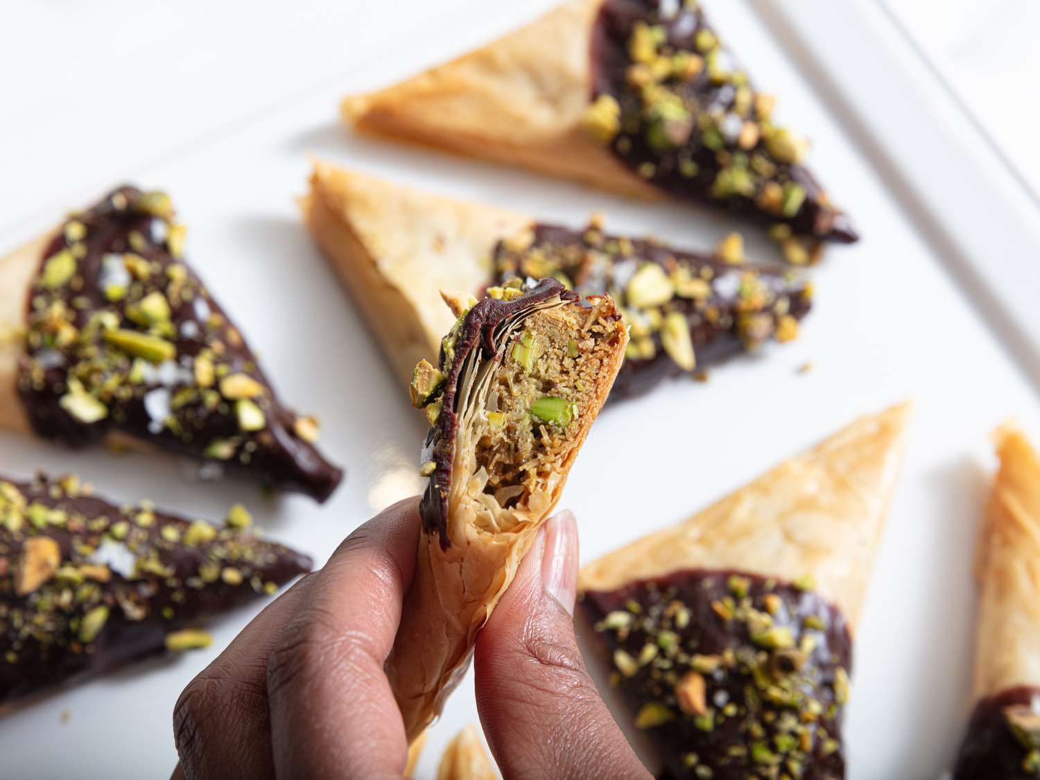 Dubai chocolate triangle with a bite taken out of it, and more triangles on the background