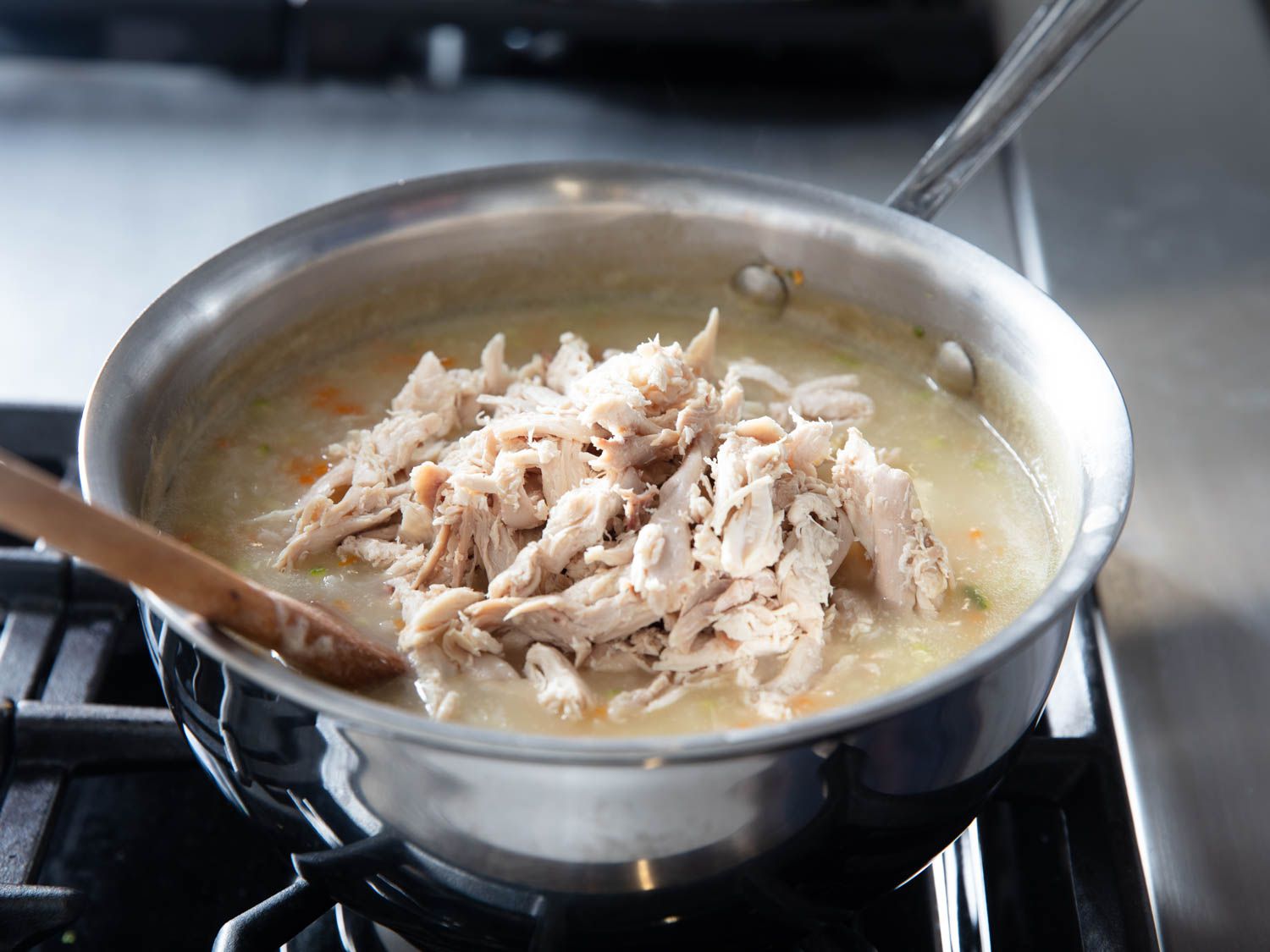 Mixing shredded chicken into a pot of Korean juk.