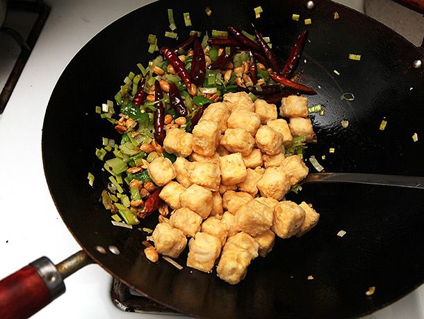 Tossing crispy vegan kung pao tofu together in a wok.