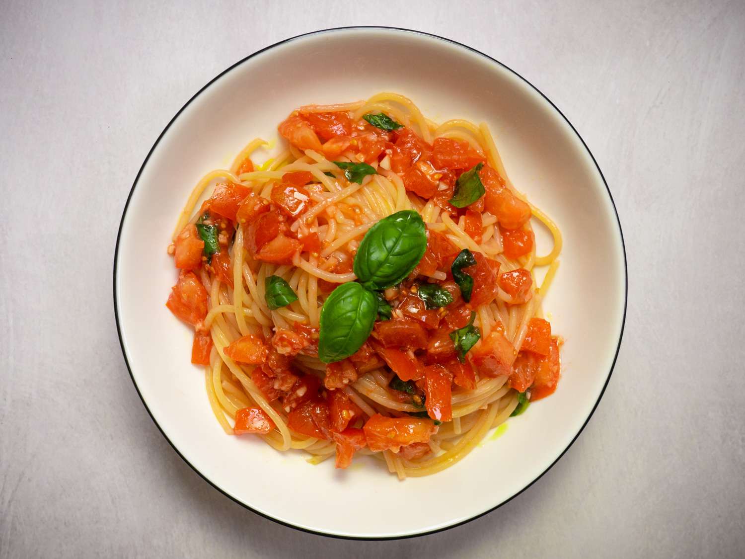 Spaghetti al Pomodoro Crudo on a plate and topped with basil leaves