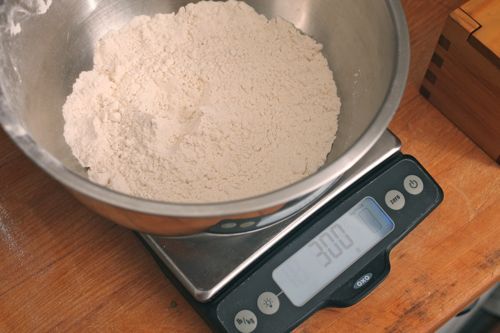 Silver mixing bowl filled with flour on top of digital kitchen scale
