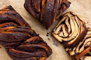 2 babkas on a parchment paper, one sliced and one whole