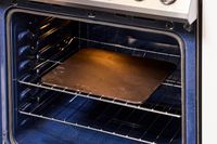 A pizza steel on an oven's rack.