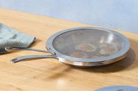 the all-clad splatter screen on a skillet with fried eggs