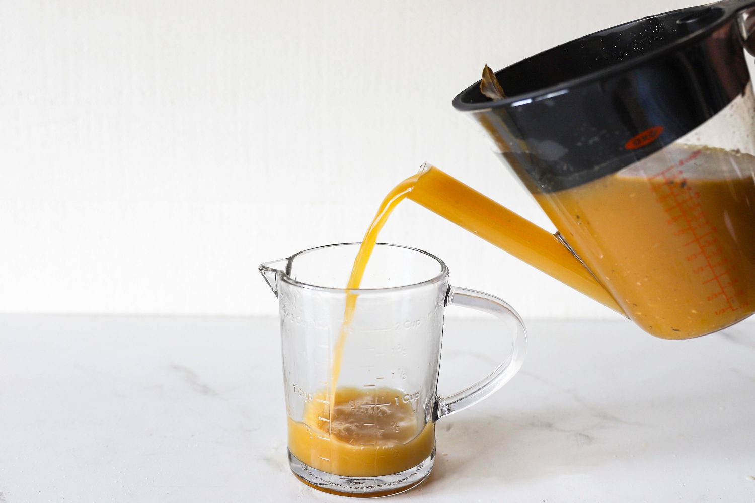 Liquid being poured from a measuring cup into another measuring cup