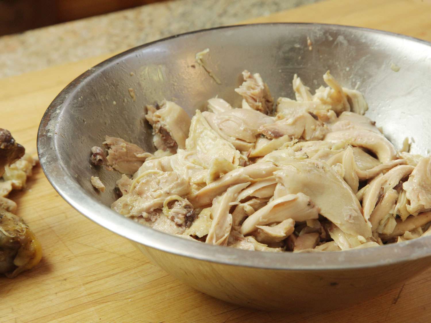 Picked chicken in a bowl, ready to add to pozole verde.