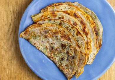 A pile of thin, folded scallion pancakes made with sourdough discard