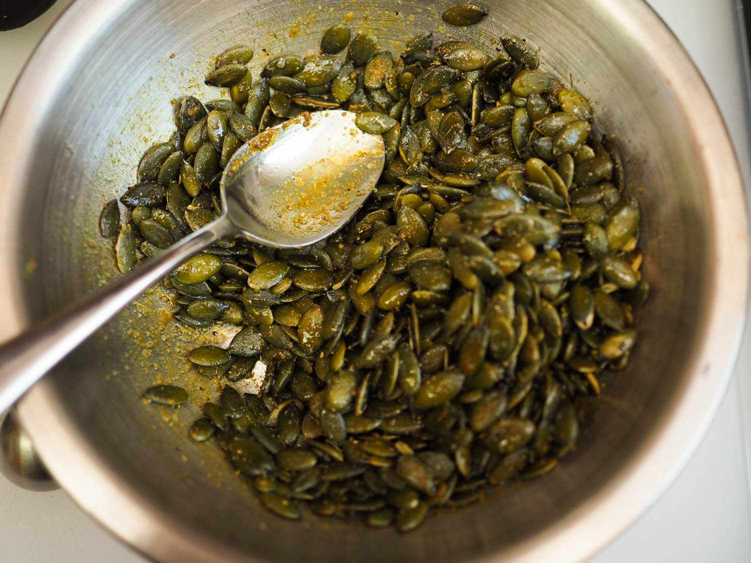 Pepitas are tossed with oil and spices.