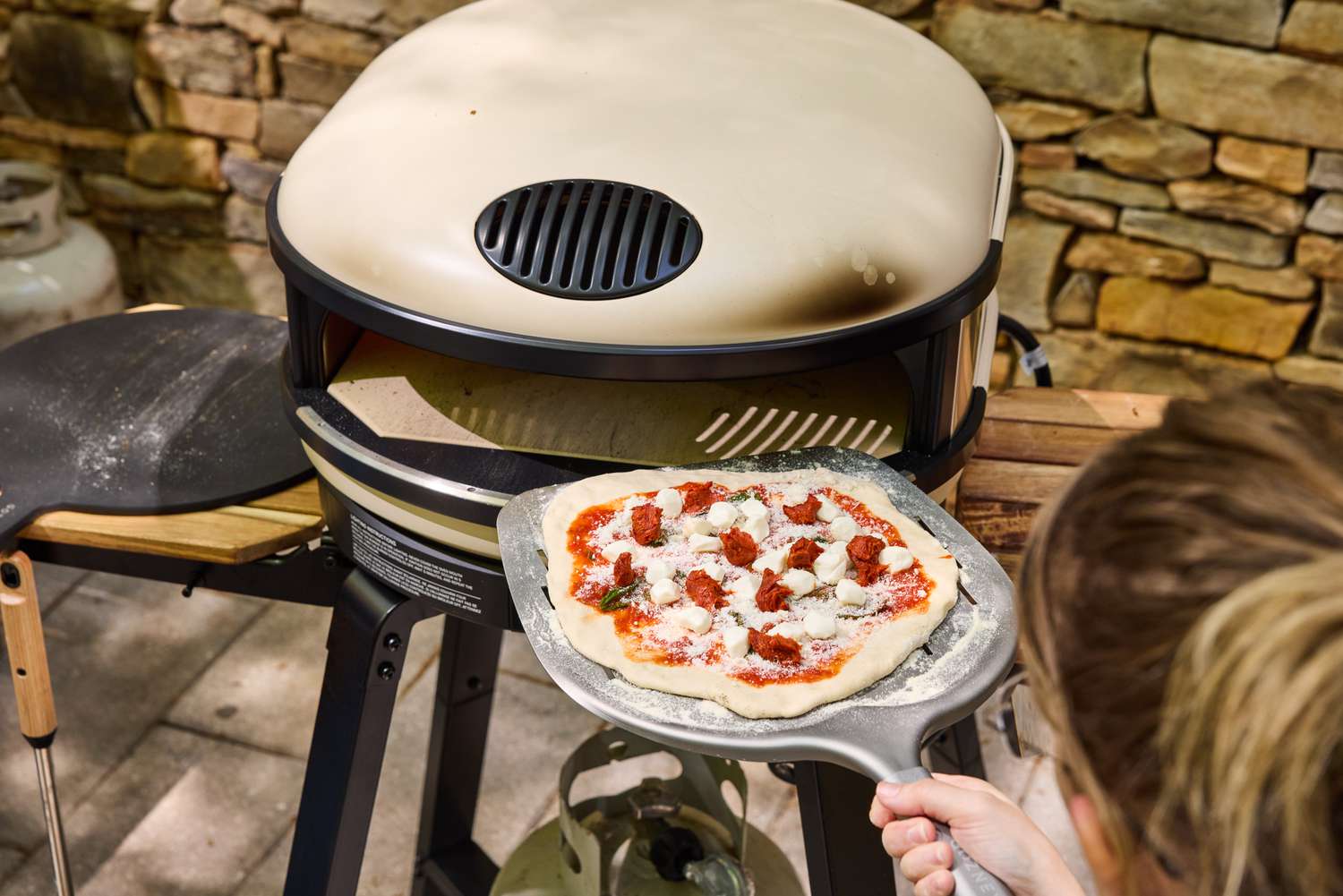 A person places a pizza into the Gozney ARC XL Compact Pizza Oven