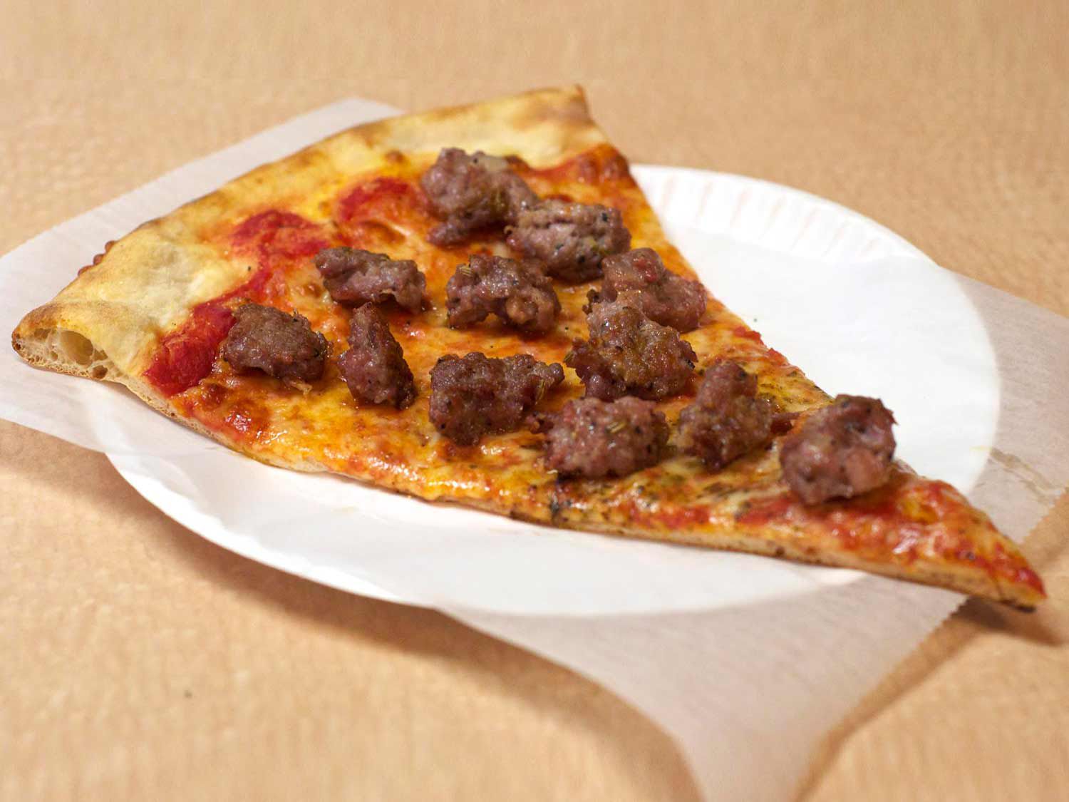 A slice topped with sausage from Louie & Ernie's