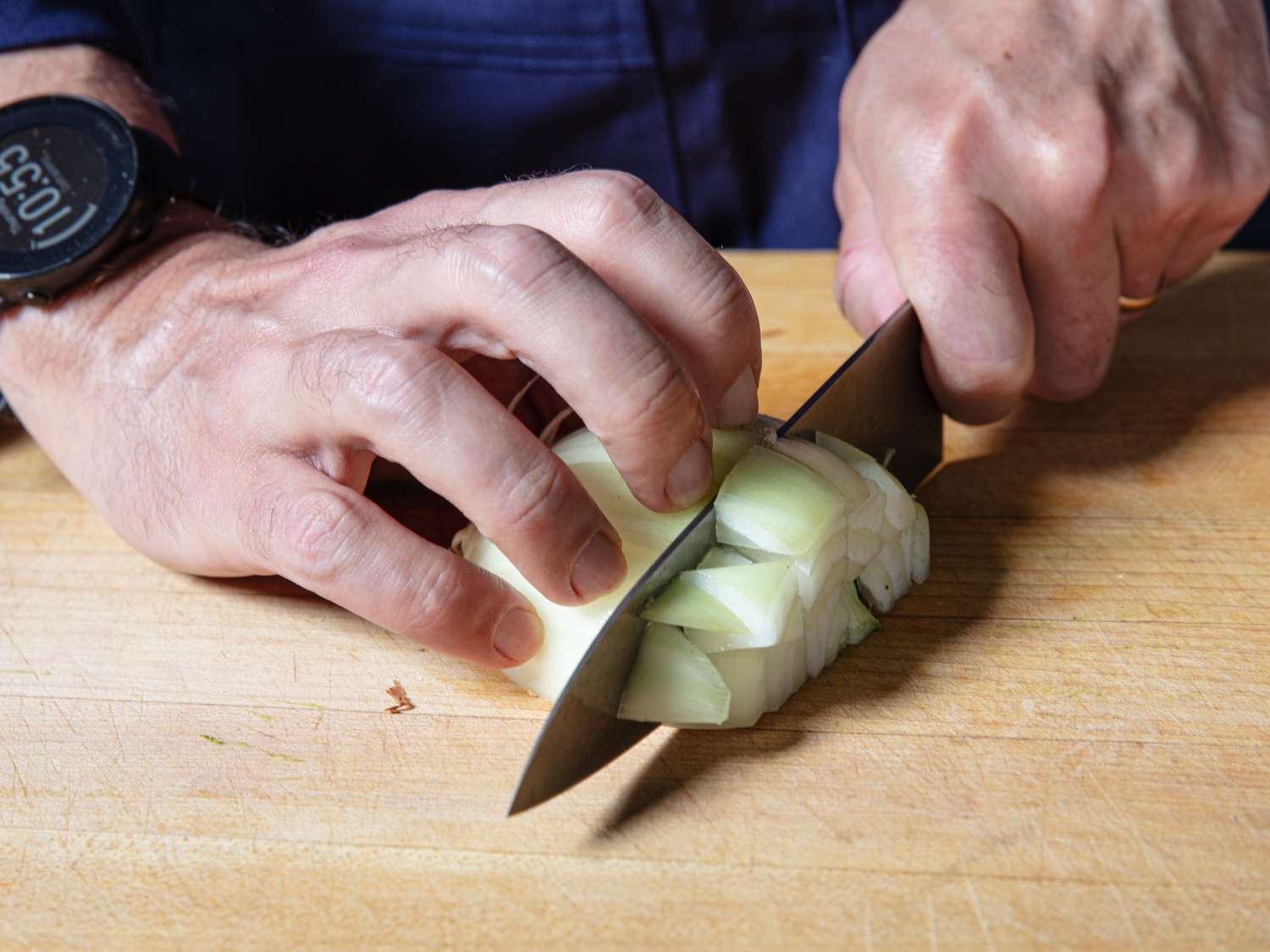 Knife making a vertical cut along X-axis of an onion cut along Y- and Z- axes to yield diced onion bits
