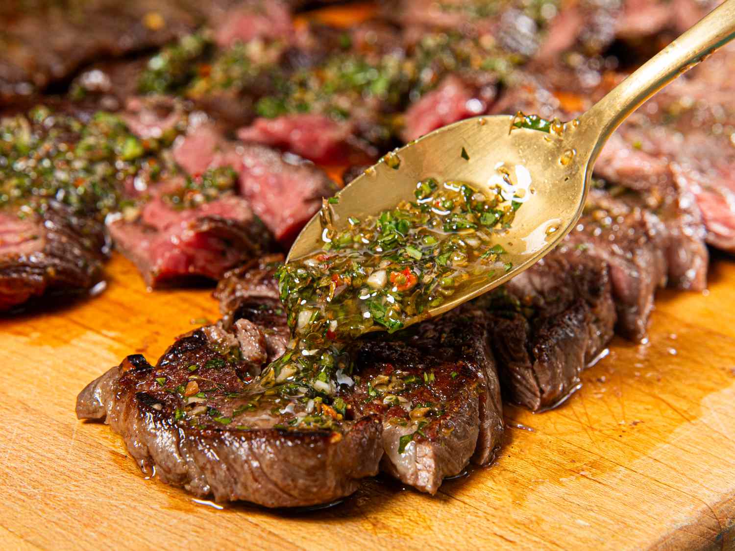 Side angle of chimichurri being spooned onto steak