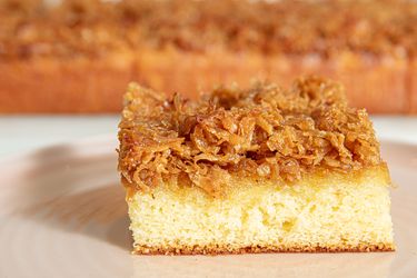 Slice of cake topped with caramelized shredded coconut on a plate