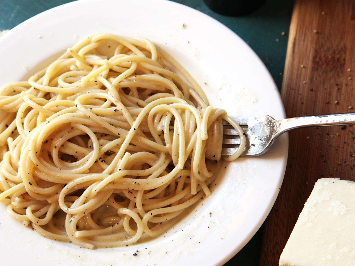 A shallow white dish of cacio e pepe with a fork.