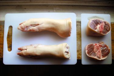 pig's feet and hocks on plastic white cutting boards. 