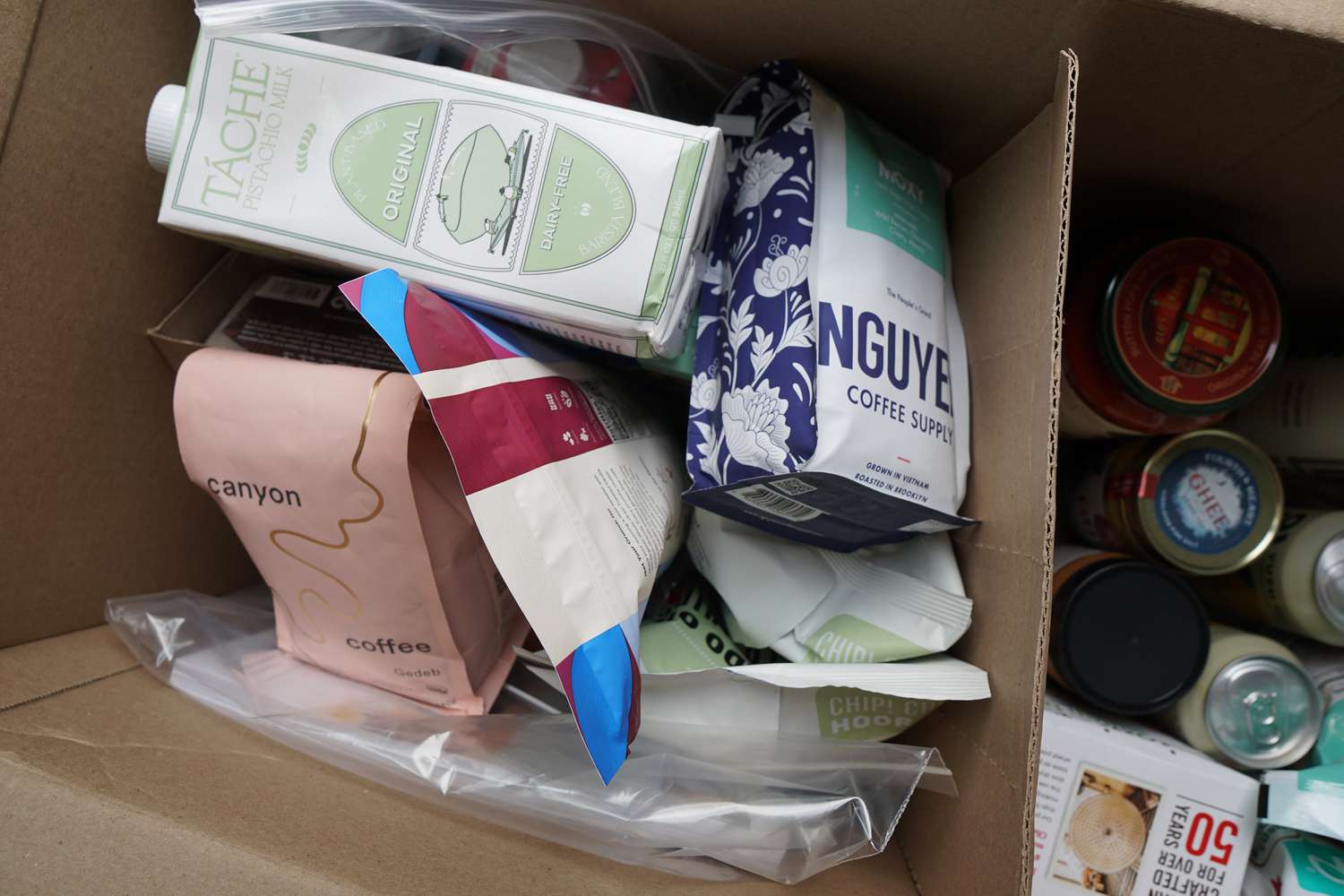a box of groceries containing coffee, pistachio milk, potato chips, and more