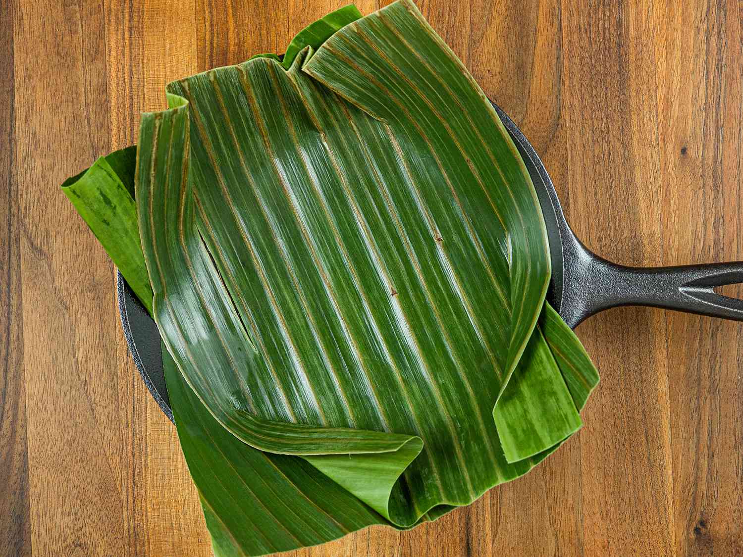 Banana leaf segments lining the bottom of a cast iron pan